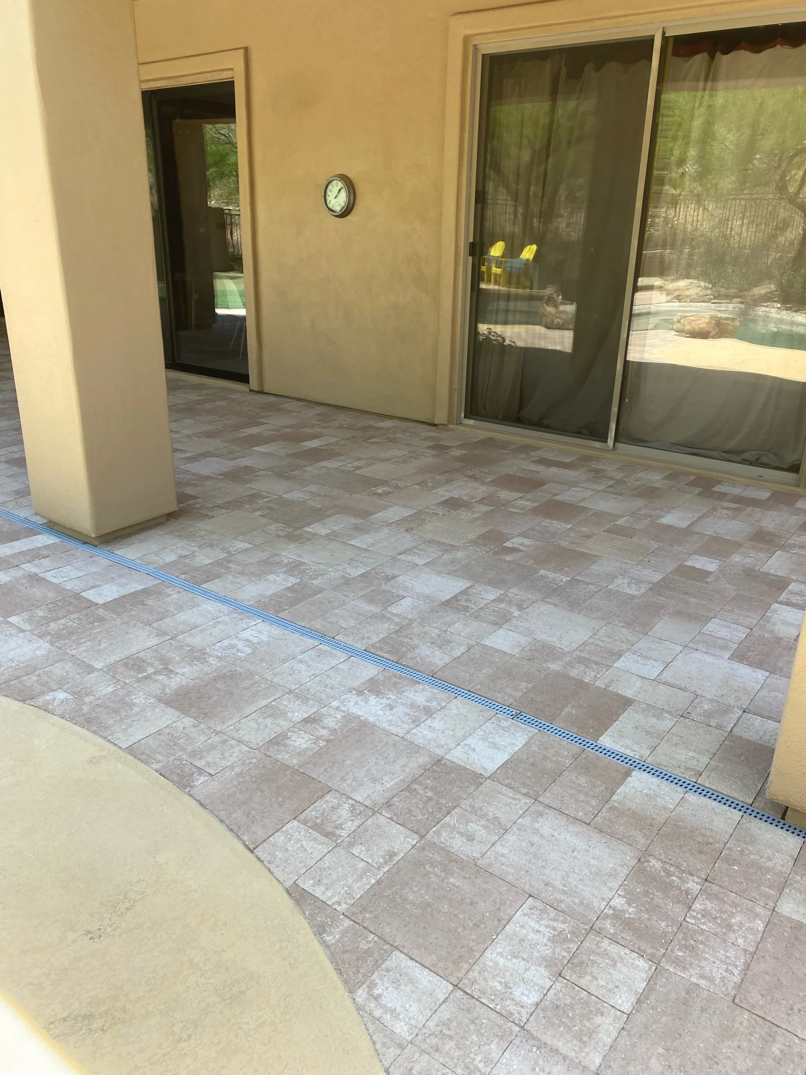 Concrete paver patio with mixed gray tones in running bond pattern, blue drainage fabric visible