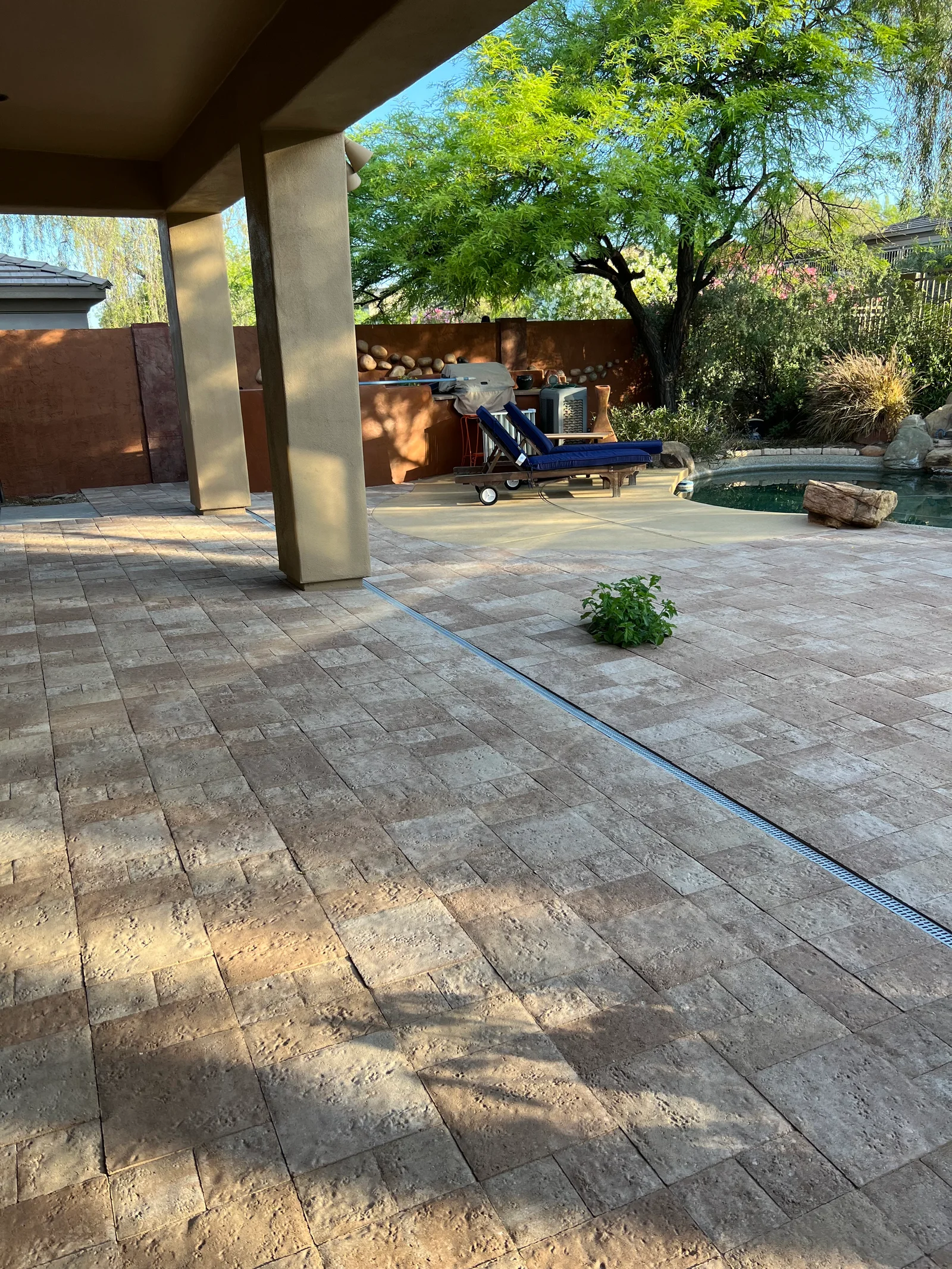Stamped concrete patio with running bond pattern, pergola structure, and steel fencing