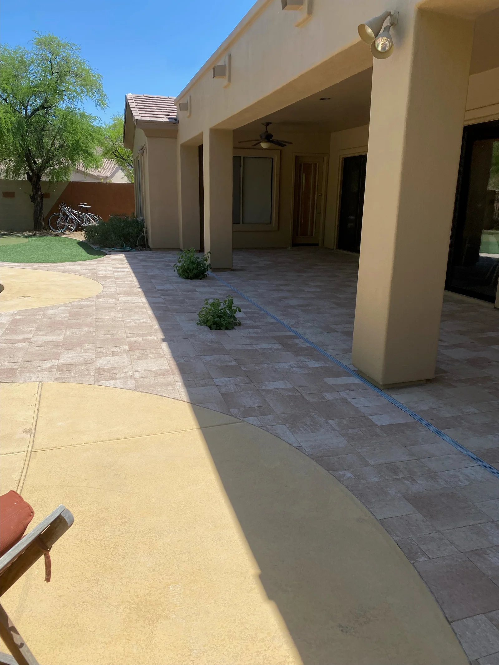 Backyard patio with mixed pavers, concrete sections, and covered porch with columns