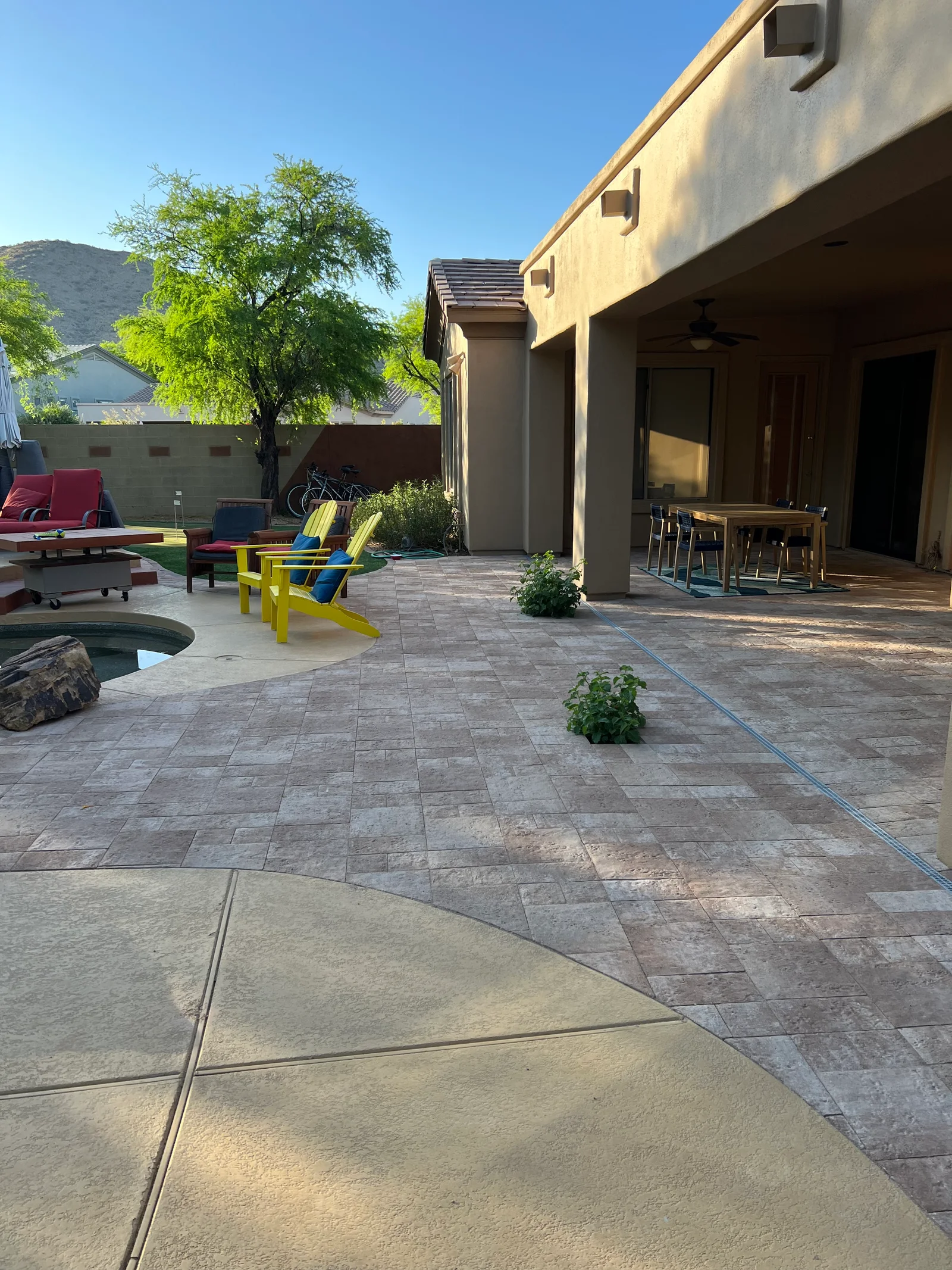 Paver patio with mixed stone formats, concrete pad, and stucco home exterior