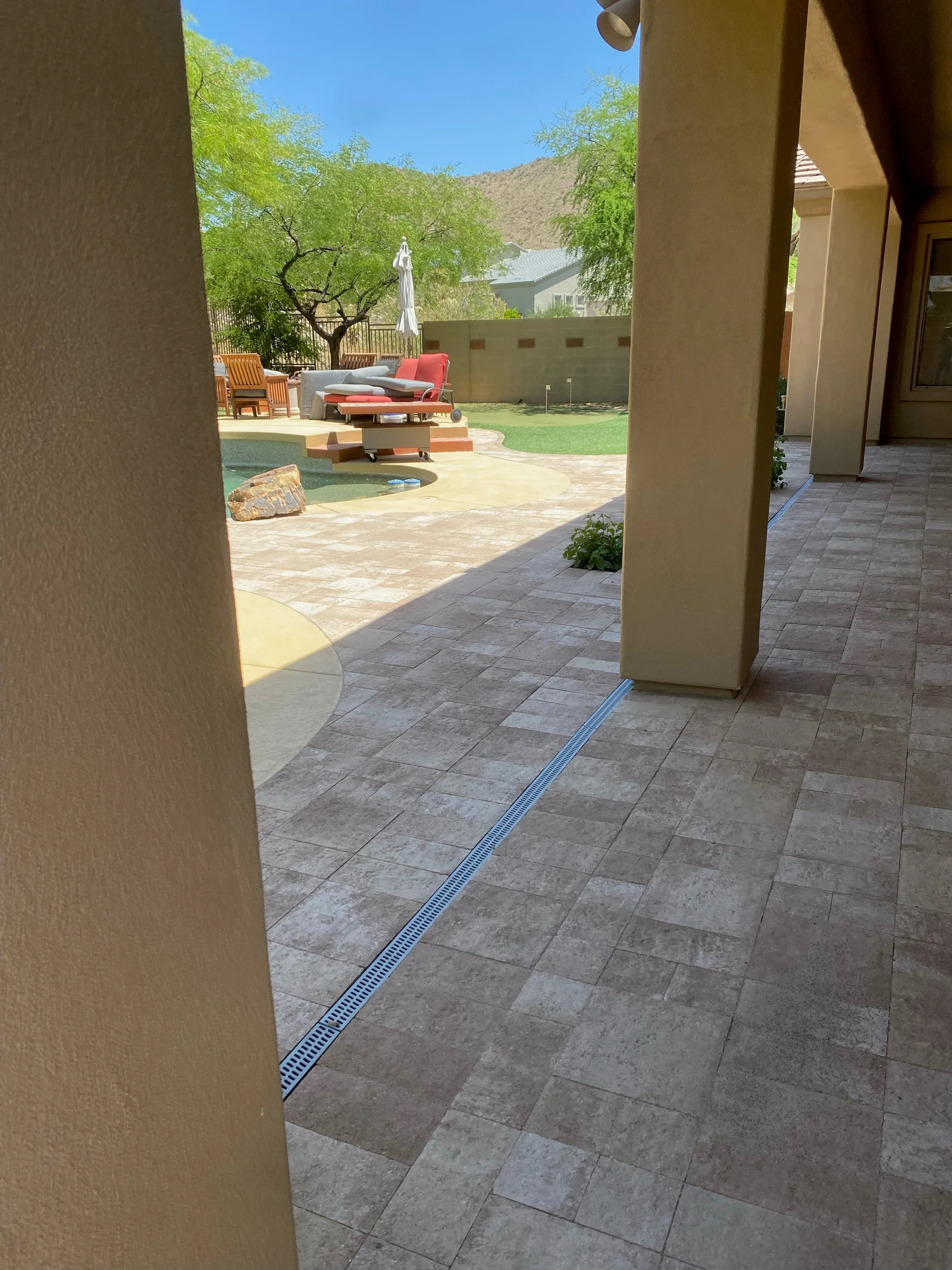 Travertine patio with linear drain, lounge seating, and desert landscape