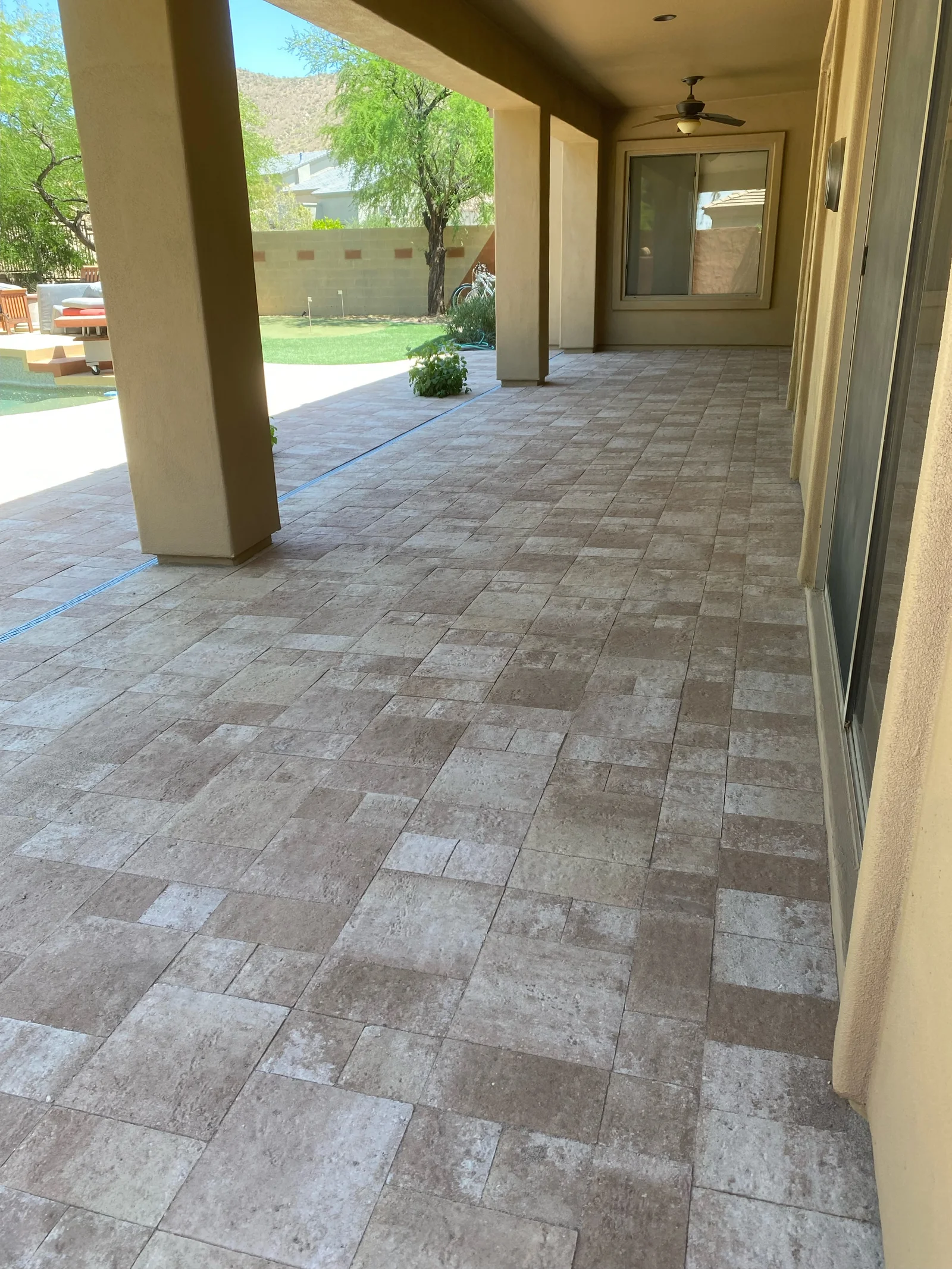 Travertine tile patio with running bond pattern, stucco columns, and glass doors